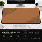 Minimal Cognac Ink desk mat beneath a monitor on a bright desk with a white keyboard and mouse.