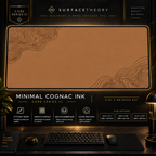 Minimal Cognac Ink desk mat in a gold-toned showcase frame above a keyboard.