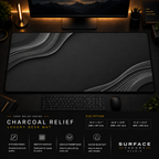 Charcoal Relief desk mat in a dark workstation with warm monitor lighting.