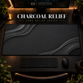 Charcoal Relief desk mat in a warm, dark workspace.