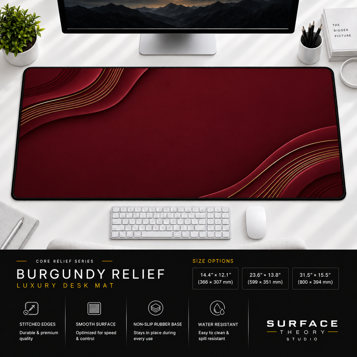 Burgundy Relief desk mat beneath a monitor on a bright desk with a white keyboard and mouse.