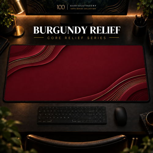Burgundy Relief desk mat in a warm, dark workspace.