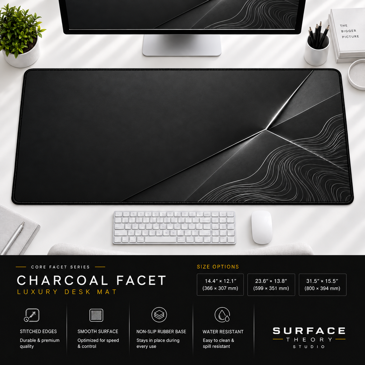 Charcoal Facet desk mat beneath a monitor on a bright desk with a white keyboard and mouse.