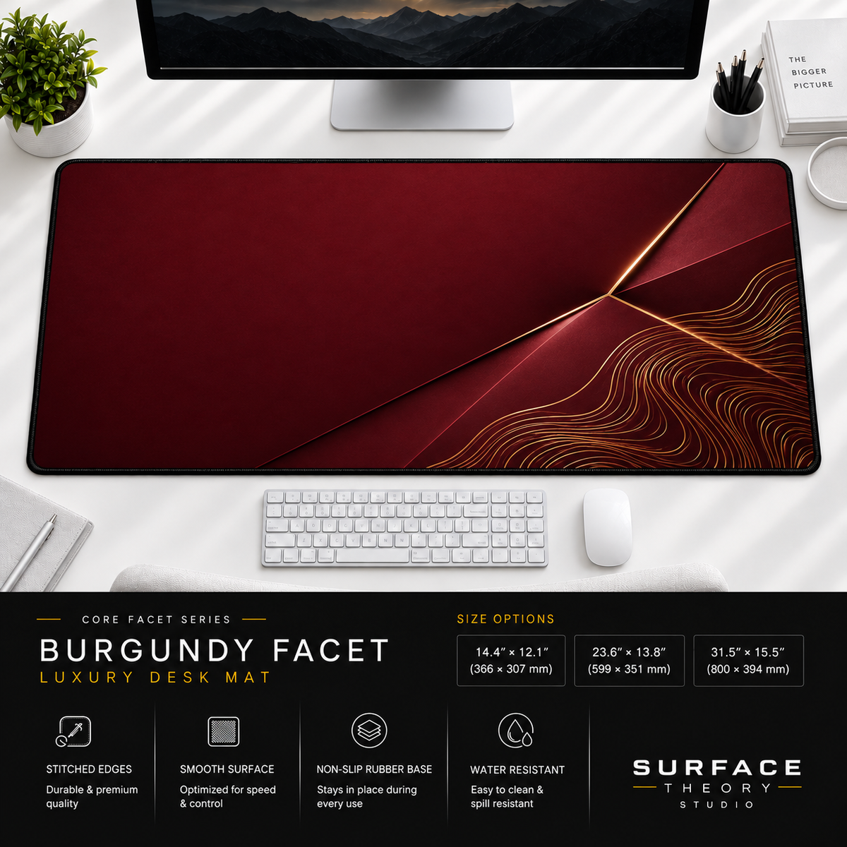 Burgundy Facet desk mat beneath a monitor on a bright desk with a white keyboard and mouse.
