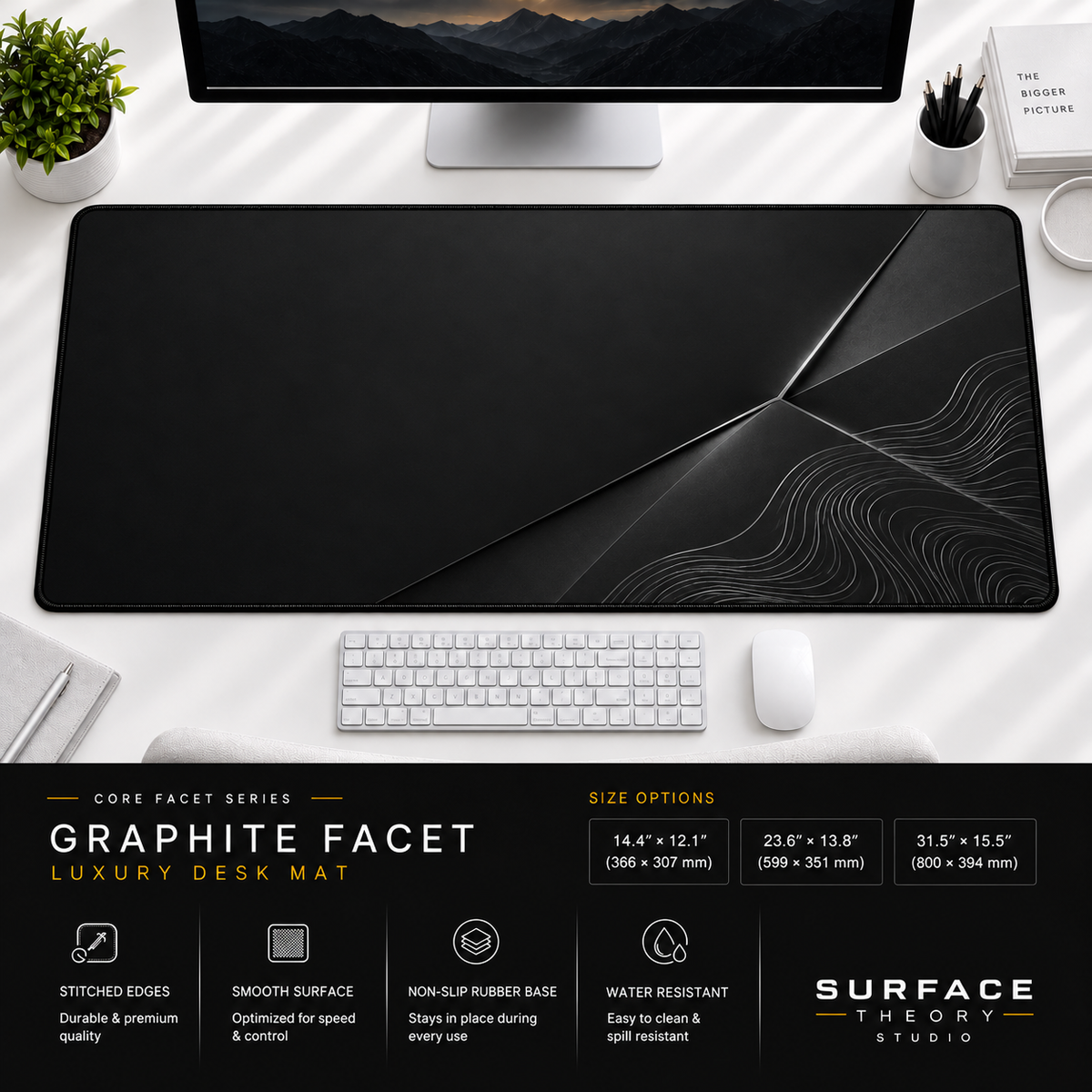 Graphite Facet desk mat beneath a monitor on a bright desk with a white keyboard and mouse.