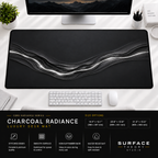 Charcoal Radiance desk mat beneath a monitor on a bright desk with a white keyboard and mouse.
