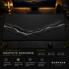 Graphite Radiance desk mat in a dark workstation with warm monitor lighting.