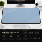 Minimal Artic Mist desk mat beneath a monitor on a bright desk with a white keyboard and mouse.