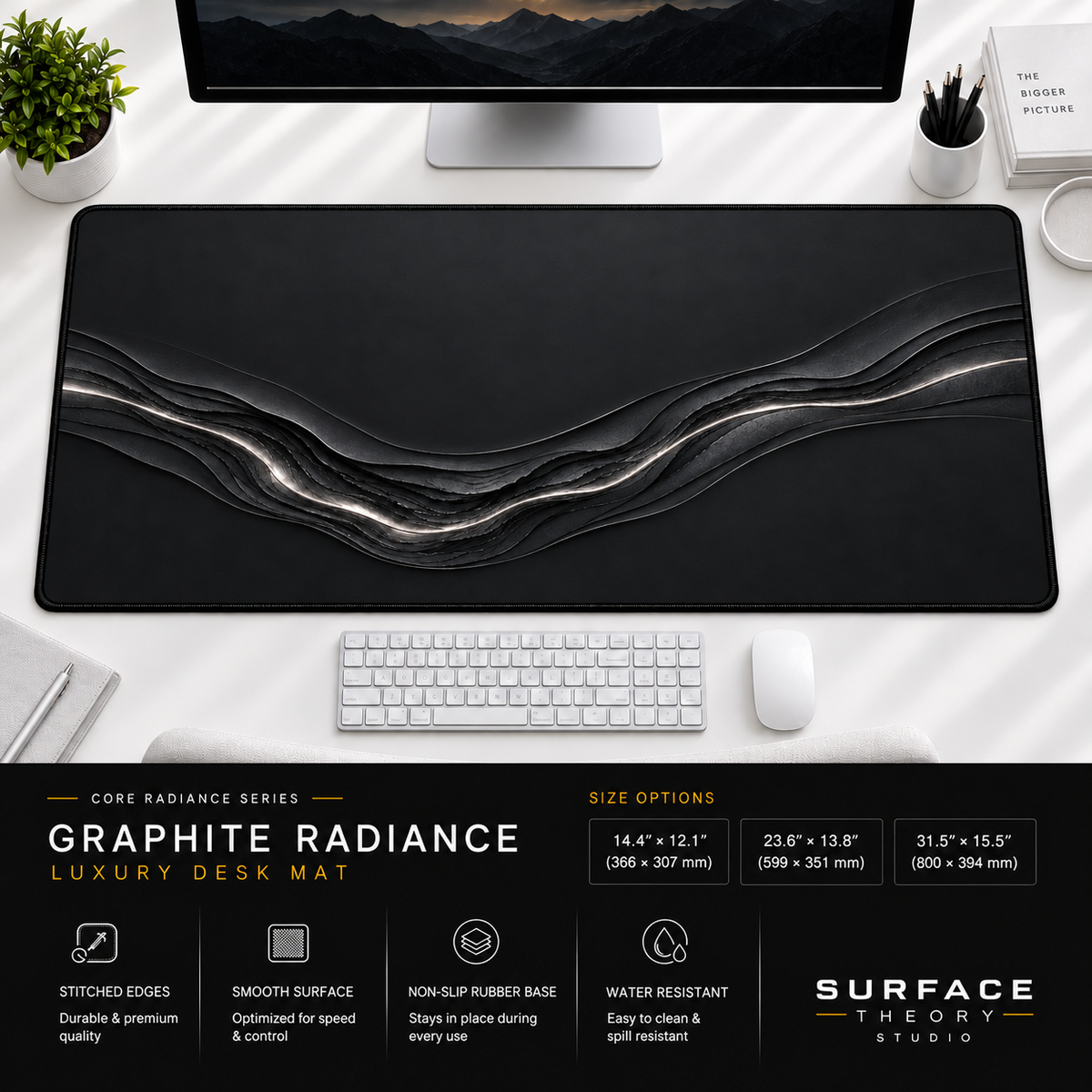 Graphite Radiance desk mat beneath a monitor on a bright desk with a white keyboard and mouse.